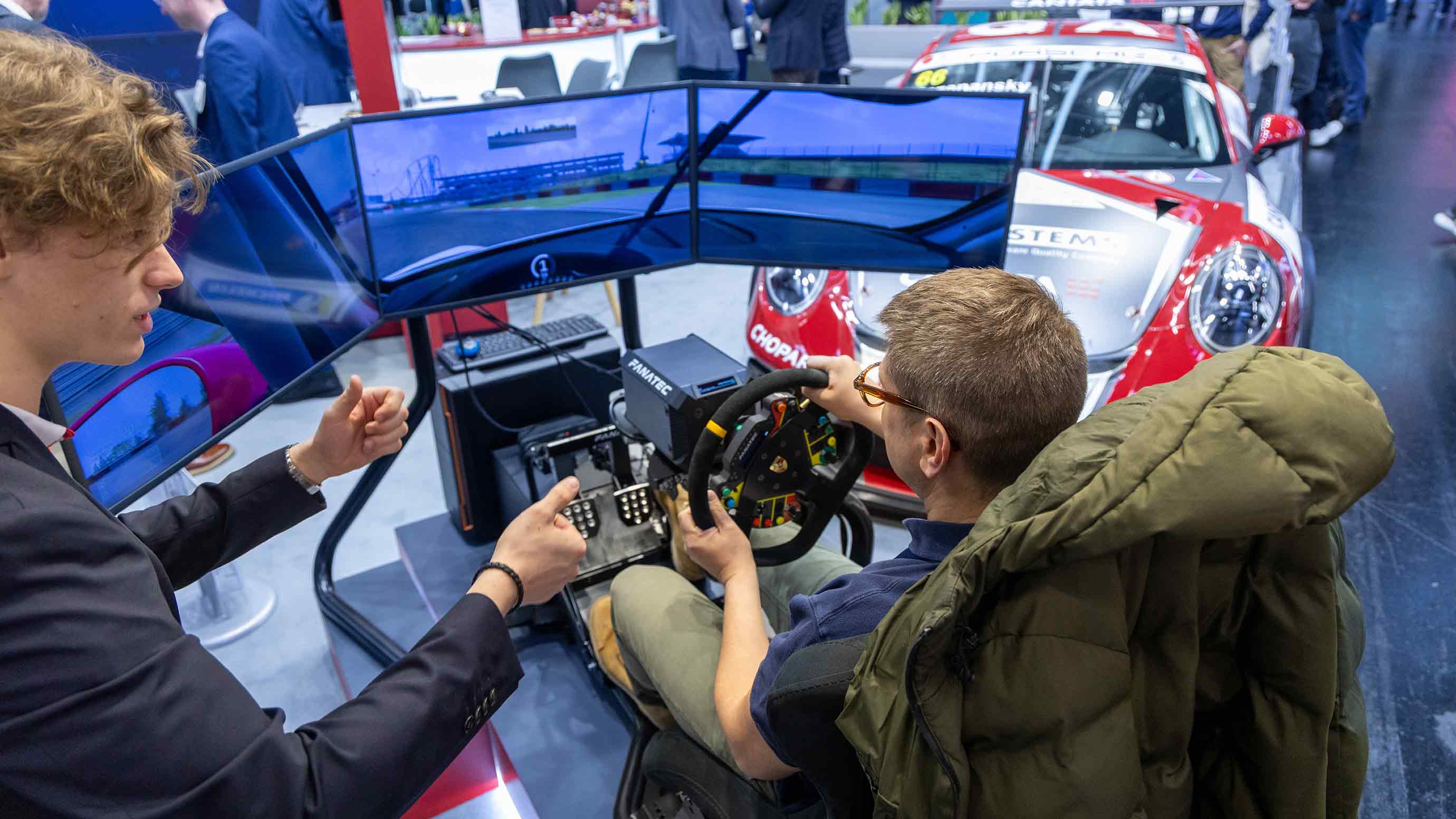 Zwei Männer steuern einen Auto-Simulator bei einer Ausstellung auf der Embedded World