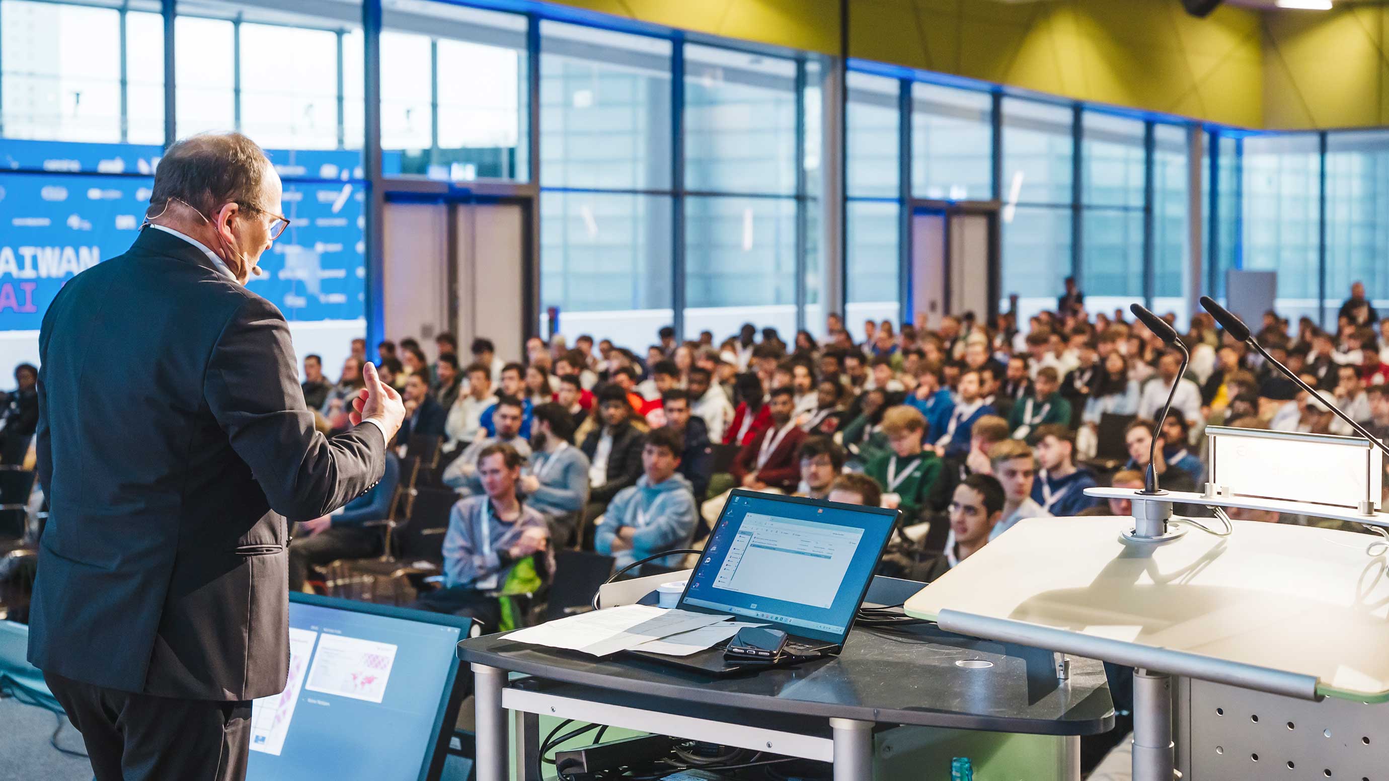 A speaker addressing a large audience at Student Day