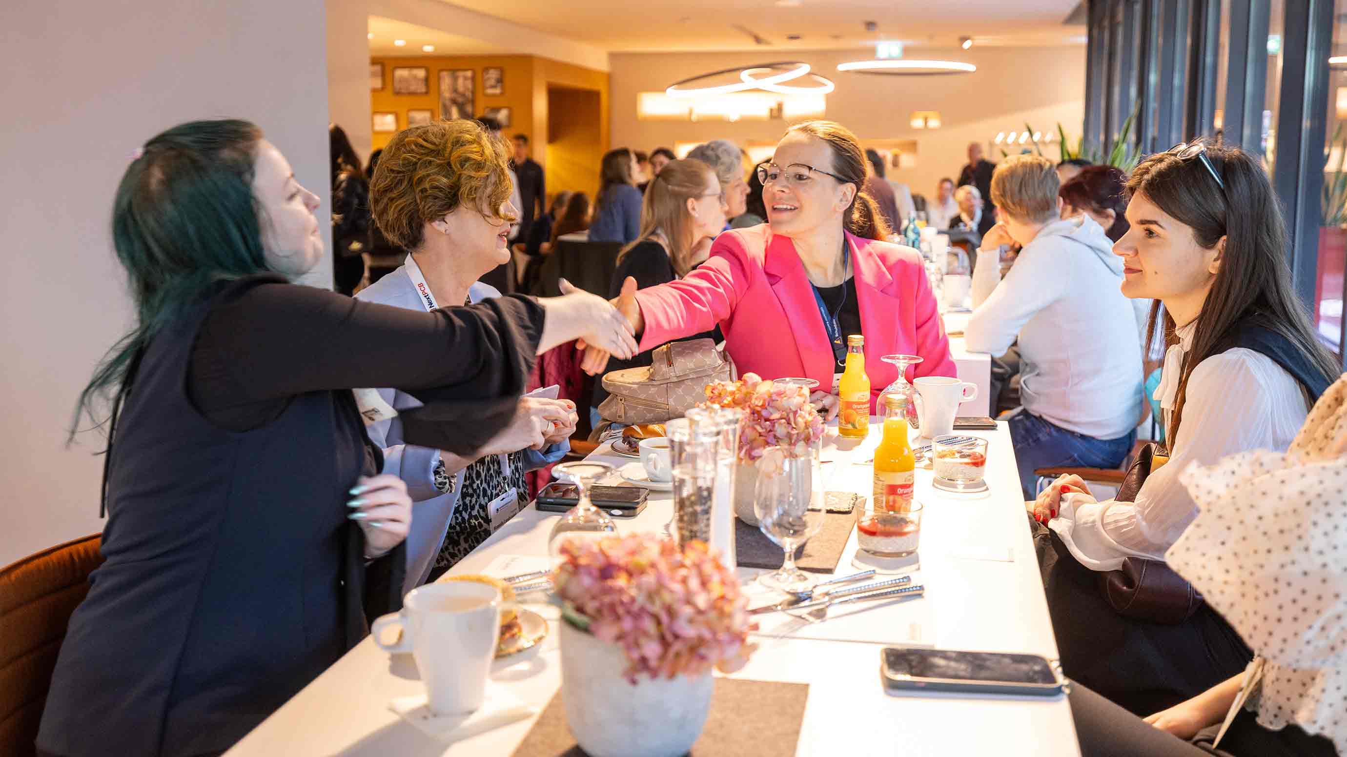 Zwei Teilnehmende begrüßen sich mit einem Handschlag bei einem Networking-Event